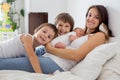 Young mother lying in bed with her newborn baby boy and his older brothers Royalty Free Stock Photo