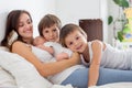 Young mother lying in bed with her newborn baby boy and his older brothers Royalty Free Stock Photo