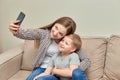 A young mother makes a selfie with her son while sitting at home on the couch. Royalty Free Stock Photo