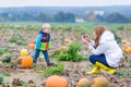 Young mother making picture of her son on pumpkin field.
