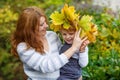 Young mother in a maple leaf wreath holding little toddler boy Royalty Free Stock Photo