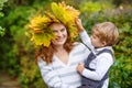 Young mother in a maple leaf wreath holding little toddler boy Royalty Free Stock Photo