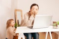 A mother on maternity leave sits at a laptop and works. A child yelling hysterically cries distracts from work. A woman is engaged Royalty Free Stock Photo