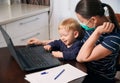 Young mother on maternity leave trying to freelance by the desk with toddler child. Royalty Free Stock Photo