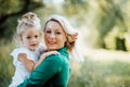 Young mother in nature holding small daughter in the arms. Copy space. Royalty Free Stock Photo