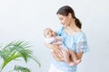 A young mother with a newborn baby gently holds it in her arms, hugging and admiring it at home, the concept of a happy family and Royalty Free Stock Photo