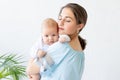 A young mother with a newborn baby gently holds it in her arms, hugging and admiring it at home, the concept of a happy family and Royalty Free Stock Photo