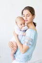 a young mother with a newborn baby gently holds it in her arms, hugging and admiring it at home, the concept of a happy Royalty Free Stock Photo