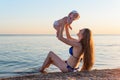 Young mother and newborn on beach on sea background. Mom catches baby. Vacation with child at sea Royalty Free Stock Photo