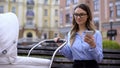 Young mother in office suit working smartphone and smiling to baby in carriage