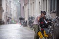 Young mother places her child on bike in the rain. Amsterdam Royalty Free Stock Photo