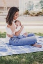 young mother playing breast feeding her baby girl outdoors in a park, happy family concept. love mother daughter Royalty Free Stock Photo