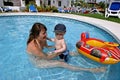 Mladý matka v detské plávanie bazén batoľa syn a nafukovacie čln 