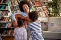 A young mother playing a guitar to her little children at home. Family, home, playtime Royalty Free Stock Photo