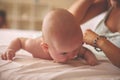 Young mother playing with her baby boy in bed. Mother working ex Royalty Free Stock Photo