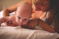 Young mother playing with her baby boy in bed. Mother working ex Royalty Free Stock Photo