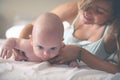 Young mother playing with her baby boy in bed. Mother working ex Royalty Free Stock Photo