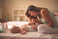 Young mother playing with her baby girl in bed. Mother enjoying Royalty Free Stock Photo