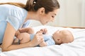 Young mother playing with her cute newborn baby in bed