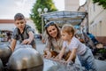 Young mother playing with her kids with fountain in city street in summer. Royalty Free Stock Photo