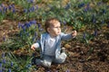 Young mother playing and talking with a baby boy son on a muscari field in Spring - Sunny day - Grape hyacinth - Riga Royalty Free Stock Photo