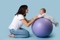 Young mother plays fitness ball with her baby Royalty Free Stock Photo