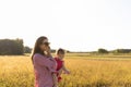 Young mother plays with her baby in a meadow