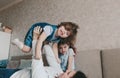 a young mother plays with her daughters lying on the sofa, lifting up a little girl on her outstretched arms. family