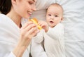 Young mother plays with her newborn son lying in bed Royalty Free Stock Photo