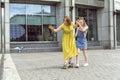 Young mother practising on skateboard in the city street. Daughter helping mum on skateboard Royalty Free Stock Photo