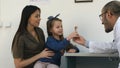 Young mother proud of her little girl and doctor giving her a lollipop after the exam