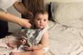 A young mother puts her baby in baby clothes