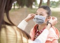 Young mother puts the mask on her daughter to prevent coronavirus