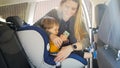 Portrait of young mother putting her toddler son in car safety seat Royalty Free Stock Photo