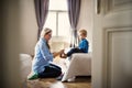 A young mother putting socks on toddler son inside in a bedroom. Royalty Free Stock Photo