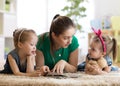 Young mother reading a book to her kids daughters. Children and mom lying on rug in sunny living room. Royalty Free Stock Photo