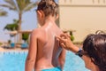 Young mother rubbing sunscreen onto her son