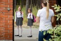 Young mother seeing of her children to school and waving to them