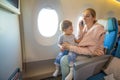 A young mother sits in an airplane chair and talks on the phone, in her arms sits a little cute baby. close-up, soft focus, side Royalty Free Stock Photo