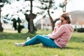 A young mother sits on the grass, hugs and kisses her baby. Recreation in the park with a child Royalty Free Stock Photo