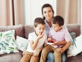 A young mother sits with two boys on the sofa in the living room and the brothers eat berries