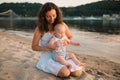 Young mother sitting on the beach with one year old baby son. Boy hugging, smiling, laughing, summer day. Happy childhood carefree Royalty Free Stock Photo