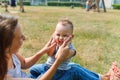 Young mother sitting face to her cute toddler son playing clapping hands in park, lifestyle fun concept Royalty Free Stock Photo