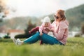 A young mother is sitting on the grass, playing with her baby. Recreation in the park with a child. Blurred background. Children` Royalty Free Stock Photo