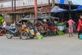 A young mother sitting on a rickshaw waiting for her driver to start her journey home