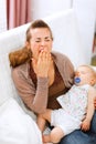 Young mother with sleeping baby on hands yawing