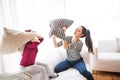 Young mother with a small girl at home having pillow fight.