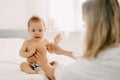 A young mother smears the baby& x27;s tummy with baby cream. Child care, childhood, parenting Royalty Free Stock Photo