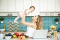Young mother smiling, cooking and playing with her baby daughter in a modern kitchen. Healthy food concept. Royalty Free Stock Photo