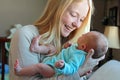 Young Mother Smiling at Newborn Baby in Home Nursery